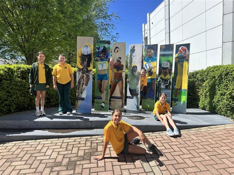 Students picture in front of sporting hero display.