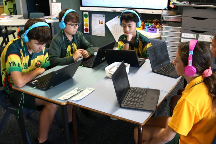 Students wearing headphones and working on laptops.
