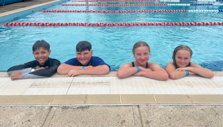 Students in the water, leaning on pool edge.