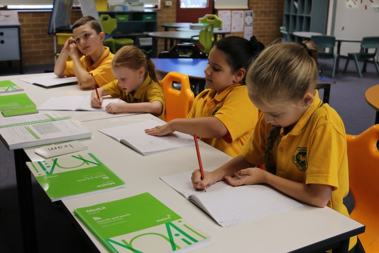 Four students working at desks in the classroom.